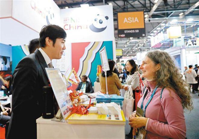 一名女子在英国伦敦世界旅游交易会中国展区与工作人员交流