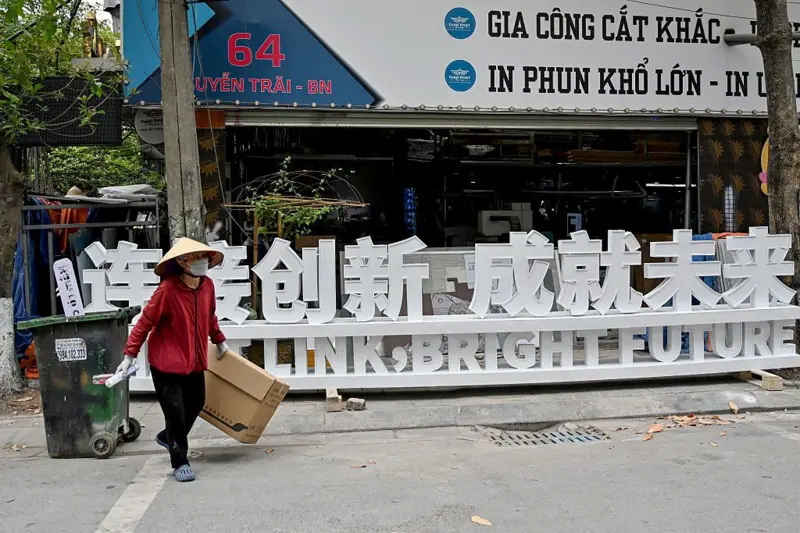 一名废品收集者走过北宁省一块中文招牌前 一名废品收集者走过北宁省一块中文招牌前