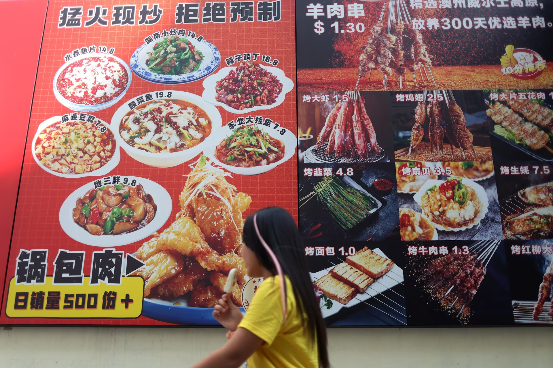 一名女子经过新加坡市中心梁城街一家中餐馆的广告 一名女子经过新加坡市中心梁城街一家中餐馆的广告